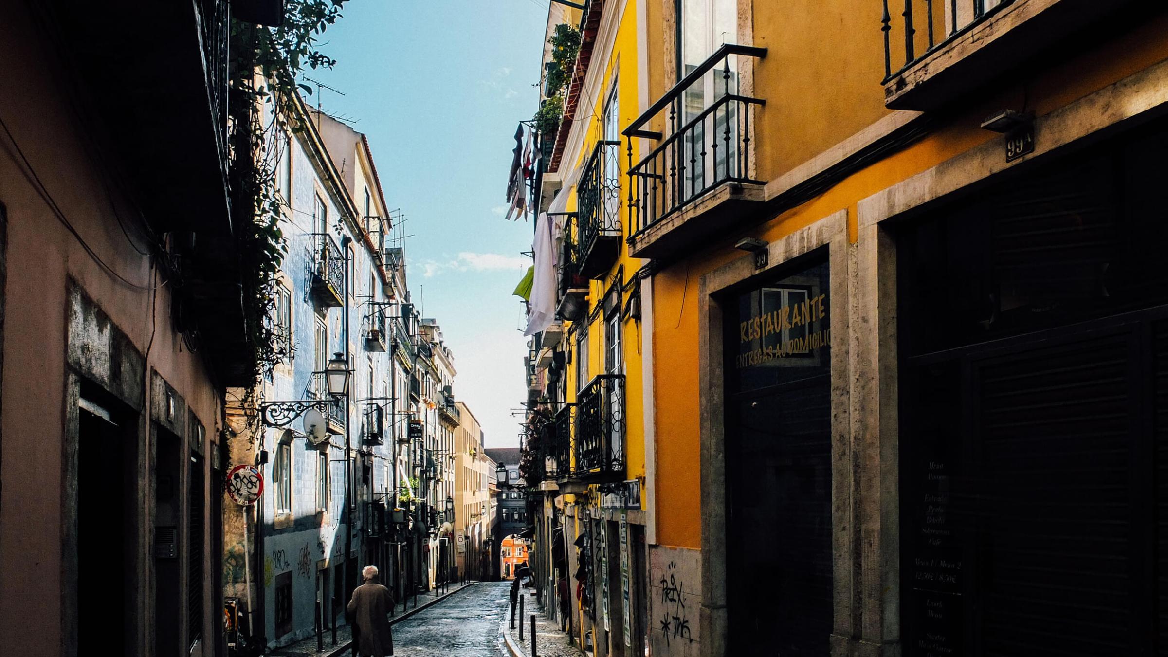 a narrow city street in Lisbon with colourful buildings